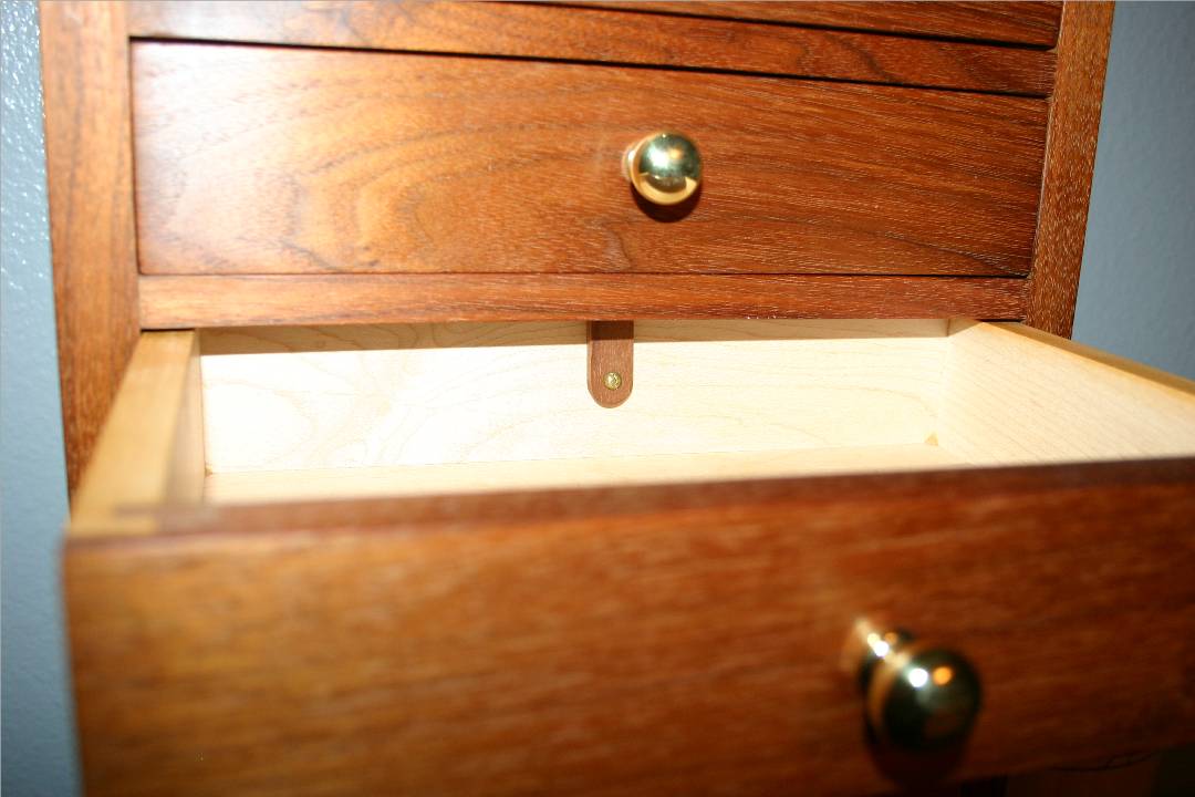 Small walnut tab at back of each drawer.